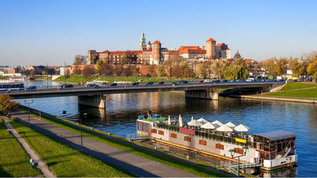 Rio Vístula, Ponte Podwawelski e um restaurante na barcaça no outono ao pôr do sol em Cracóvia - Polônia