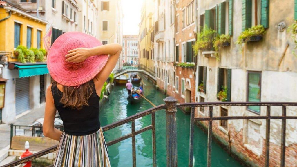 Mulher aprecia a vista de um canal com passagem de gôndola em Veneza, Itália.